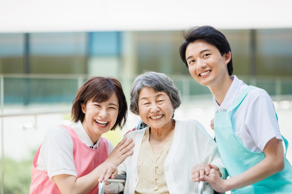 微笑む高齢女性と二人の職員